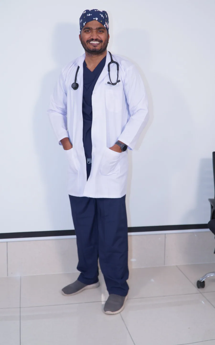 Dr. Akif standing in scrubs and a white coat